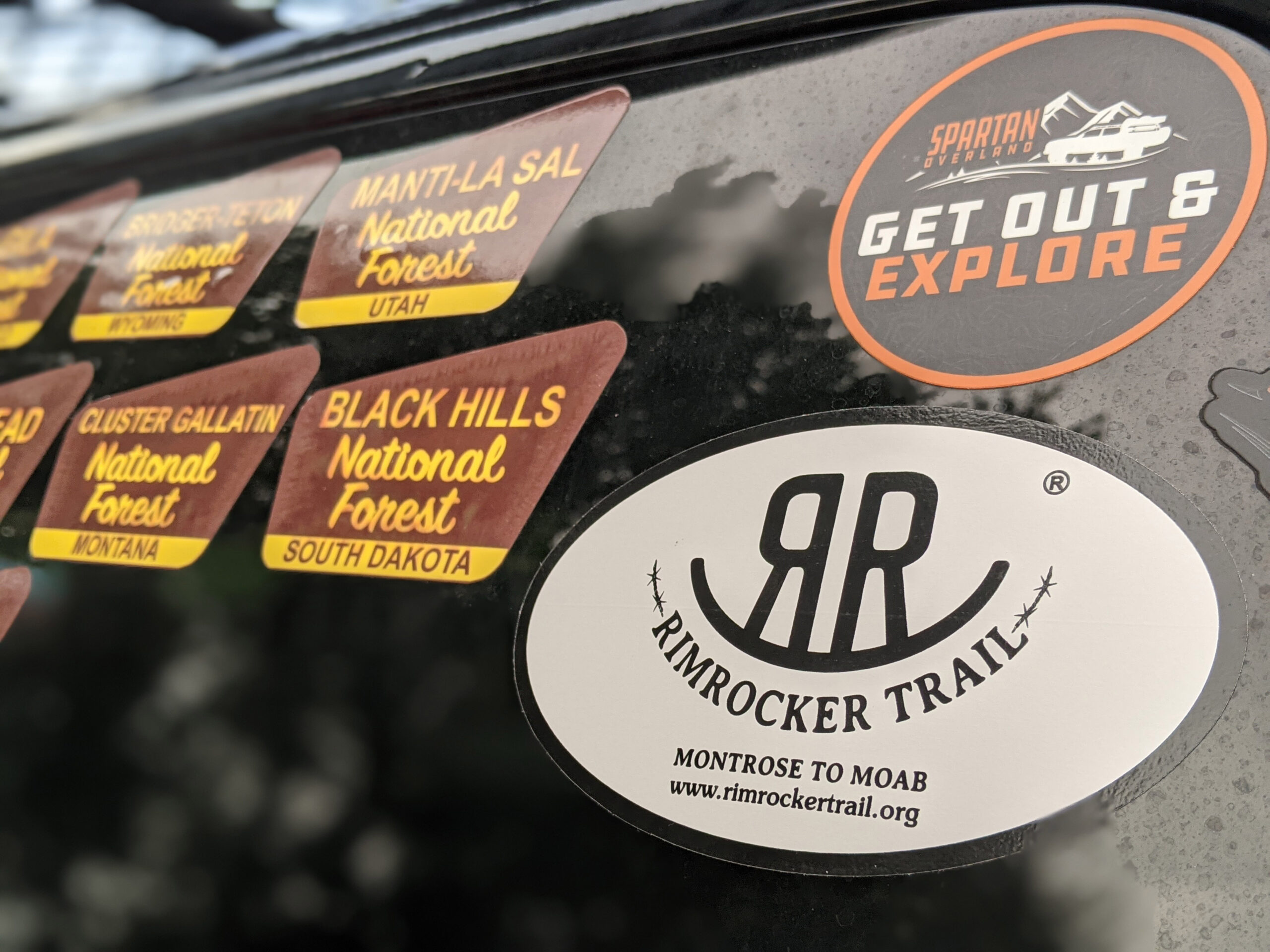 Bumper stickers on a vehicle, including a Rimrocker Trail bumper sticker